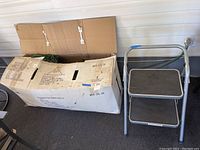 Closed original box for the pre-lit artificial Christmas tree with box partially open, showing folded tree inside.