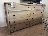 Front view of the dresser showcasing eight drawers with bronze knobs and light wood finish.