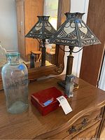 Overall lot on wooden dresser showing lamp, bottle, box, and vase.