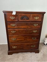 Front view of the five-drawer wooden dresser showing carved fan detail and brass handles