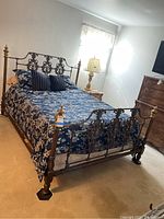 Full view of the fully assembled queen sized metal bed frame with bedding in a bedroom setting.