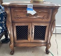Front view of the wooden nightstand showing drawer with decorative carving and two lower cabinet doors with wire mesh.