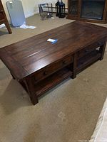 Full angled view of coffee table showing plank top, drawers, shelf