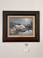 Full view of the framed print showing the snowy night scene with the cottage and lamppost.