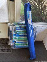 Tommy Bahama umbrella in carry bag leaning against wrapped chairs