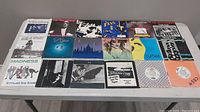 Overview photo of 18 seven-inch vinyl records with picture sleeves arranged on a table.