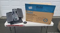 Cubii elliptical machine and original cardboard box on a white table outdoors.
