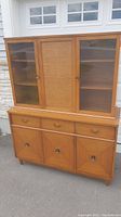 Full frontal view of the midcentury wood china hutch with upper glass doors and lower cabinets and drawers