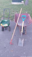 Full lot including wheelbarrow, spreader, shovel, and garden hoe on pavement with grass in background