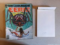 Six issues of Eerie Magazine stacked and arranged with a note showing code 154.