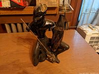 Front view showing man with spear and drum atop panther