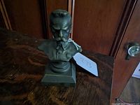 Front view of the bronze bust sculpture showing soldier's face, uniform, and chest badge.