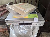 Front view of Go Video DVD/VCR combo unit with sealed documents on top