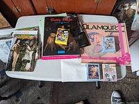Photo showing Betty Page memorabilia on a table including magazines, books, playing cards, and pin-up card set.