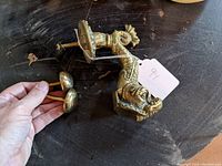 Top view of heavy brass sea creature/dolphin door knocker with mounting screws held in hand.