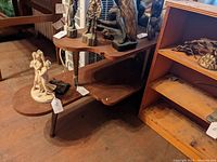 Photo showing the full 2-tier table with asymmetrical wooden shelves and several sculptures placed on top.