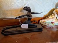 Side angle of the lamp showing the nude female figure kneeling with arms outstretched holding a rod, dark material base, and frosted circular glass shade behind.