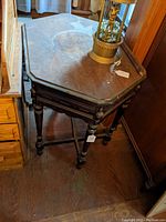 Oblong hexagonal wooden side or lamp table with turned legs and stretchers. Dark finish with wear on the top surface visible.