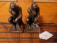 Front view of both bronze The Thinker bookends showing seated male figures with contemplative poses and dark brown patina.