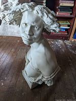 Front angled view showing facial expression and hair detail of plaster bust statue of fierce woman.