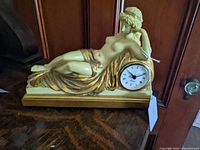 Front angled view of plaster figurine showing the nude reclining woman and embedded clock on the rectangular base.