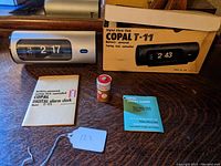 Overview showing Copal clock, original box, two manuals and vintage battery