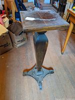 Front perspective of the wooden pedestal with square top and turned column showing overall shape and condition