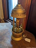 Front and side view of the vintage rain lamp showing the bathing lady figure, faux greenery, and gold-tone top and base.