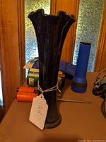 Full view of the black amethyst glass vase standing upright among other items.