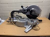 Side angle photo showing the full saw with metal base, sliding arm, and power cord.