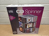 Front view of sealed product box showing branding, capacity of 132 CDs, and an image of the CD spinner loaded with CDs.
