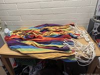 Colorful striped fabric hammock folded on a table showing thick white cotton ropes at one end