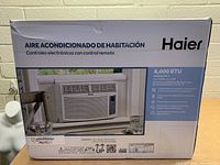 Front side of the Haier 8000 BTU air conditioner box showing product image and features in Spanish, mentioning electronic controls with remote control.