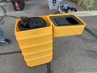 Stack of four large yellow plastic wheeled carrying cases used for storing and transporting convention display components.