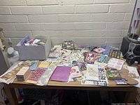 Wide view of assorted craft supplies laid out on table including sticker sheets and crafting materials