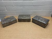 Photo of three silver plated jewelry boxes arranged side by side showing front and top.