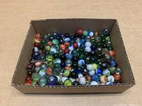 Box of assorted glass marbles showing a variety of colors and patterns.
