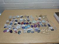 Wide view of the entire lot with multiple smooth stones laid out and hanging crystals grouped on the right side
