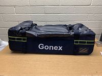 Side view of black Gonex travel duffel bag, showing brand name and side pocket with zipper.