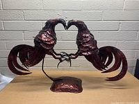 Full view front photo of metal rooster statue placed on table with concrete brick wall background