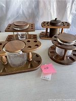 Four mid-century styled walnut wood pipe stands with glass canisters for pipe tobacco, each designed to hold 6 or 8 pipes with circular slots around the base.