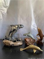 Front view of all six dolphin figurines displayed on a black surface with white backdrop