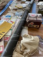 Photo showing Hartnell fishing rod protective tube labeled 'Hartnell', Berkeley 300 fishing reel box, assorted packets of fishing hooks and swivels in original packaging, and a canvas pouch bag.