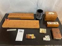 Top view of two wooden cribbage boards with pegs, several sets of dice, leather card cases, and small box labeled 'Mexico'