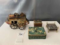 Overhead view of all 4 music boxes: metal stagecoach, 2 Swiss alpine scene boxes, and plexiglass box.