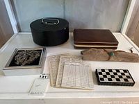 View of all game items including black poker chip case, travel chess wooden box, leather backgammon case, scorecards, and magnetic game