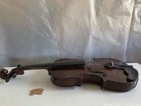Side view of pre 1955 child's violin showing the dark brown wood finish and some surface wear and scratches