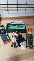 Full lot with multiple vintage GI Joe dolls, boxes, and accessories displayed on the floor.