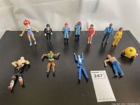 Overview of 12 assorted vintage action figures on black surface