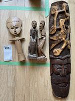 Seven wooden statues arranged on floor showing size and detail